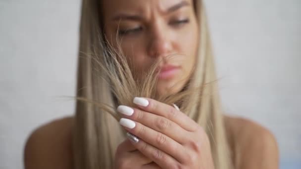 Mulher com problema de cabelo. A menina sentada em casa, percebe que o cabelo está em mau estado . — Vídeo de Stock