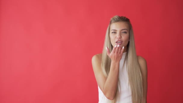 Sorridente giovane donna che invia aria bacio alla fotocamera isolato su sfondo rosso — Video Stock