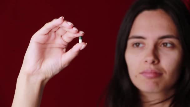 Primer plano de una mano sosteniendo píldoras de color en el fondo — Vídeos de Stock