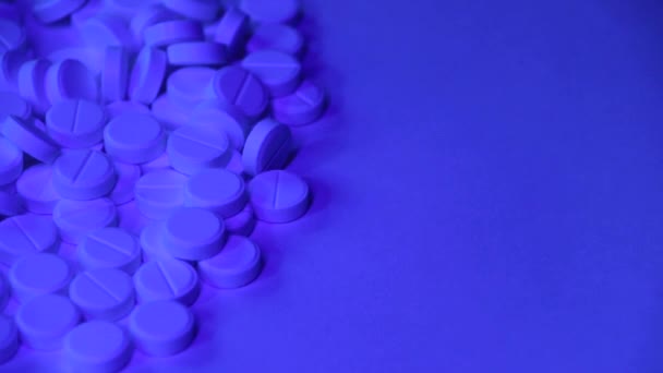 依存の概念。赤青のネオンライトを持つ多くの白い錠剤. — ストック動画