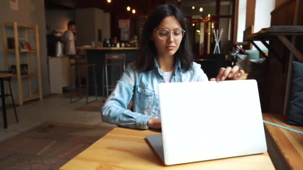 Schöne Brünette mit Laptop in Café — Stockvideo