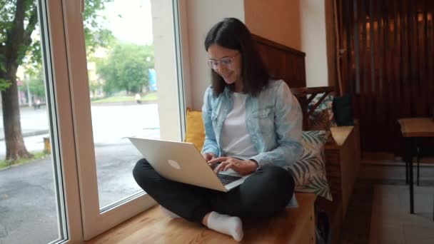 Schöne Frau sitzt mit tragbarem Netzbuch in moderner Café-Bar, junge charmante Freiberuflerin — Stockvideo