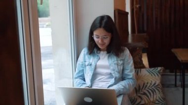 Modern kafe barda taşınabilir net kitap ile oturan güzel kadın, genç büyüleyici kadın freelancer