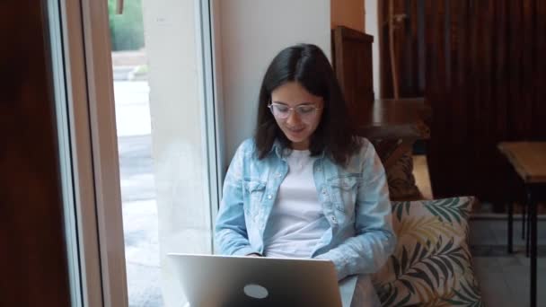 Beautiful woman sitting with portable net-book in modern cafe bar, young charming female freelancer — Stock Video