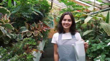 Kız bahçıvan kamera bakar ve gülümsüyor, çiçek sulama için bir sulama olabilir tutarak.