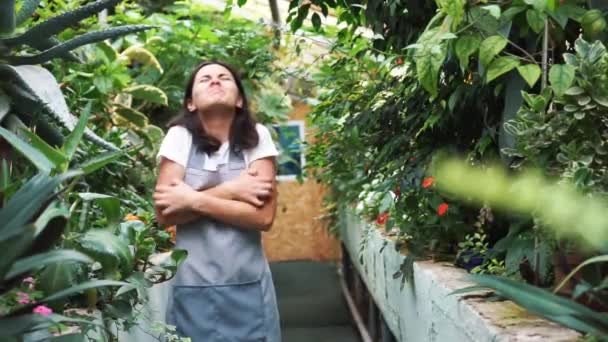 Ta dívka ve skleníku v zástěře, svědčící o pylových rostlinách. Alergická na květiny — Stock video