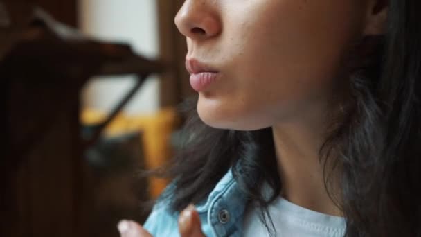 Chica en un café frente a un ordenador portátil comiendo chocolate . — Vídeos de Stock