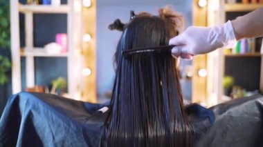 Kuaförlü bir güzellik salonunda bir kız. Salonda saç bakımı kavramı, keratin, saç düzleştirme.