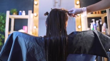 Kuaförlü bir güzellik salonunda bir kız. Salonda saç bakımı kavramı, keratin, saç düzleştirme.