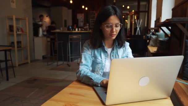 Hermosa morena usando portátil en la cafetería — Vídeos de Stock