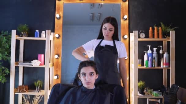 Una ragazza in un salone di bellezza con un parrucchiere. Il concetto di cura dei capelli nel salone, cheratina, stiratura dei capelli . — Video Stock