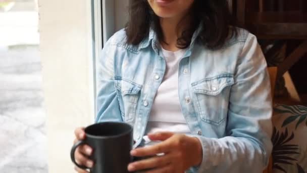 Брюнетка пьет кофе у окна — стоковое видео