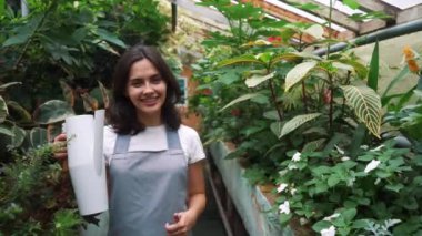 Kız bahçıvan kamera bakar ve gülümsüyor, çiçek sulama için bir sulama olabilir tutarak.