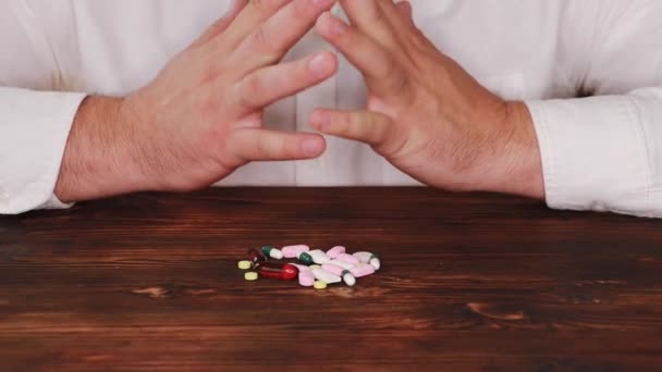 El médico escoge una píldora de un montón de dispersos. El adicto elige una pastilla. Las tabletas están dispersas en la mesa . — Vídeos de Stock
