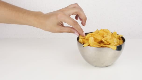 Female beautiful hands with take potato chips from a deep plate. Unhealthy food, fast food — Stock Video