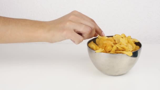 Женские красивые руки с картофельными чипсами из глубокой тарелки. Нездоровое питание, фаст-фуд — стоковое видео