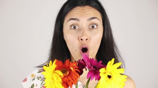 Dziewczyna twarz bliska z kwiatów bukiet. Portret całkiem młodej kobiety wąchania bukiet kwiatów na szarym tle — Wideo stockowe