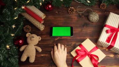 Ahşap arka plan. Üst te. Noel tatili dekorasyonu ile masada yatan yeşil ekranlı siyah akıllı telefon.