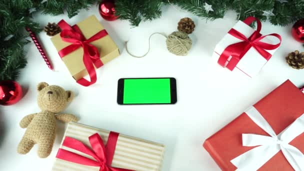 Деревянный фон. Вид сверху. Черный смартфон с зеленым экраном лежит на столе с рождественским украшением . — стоковое видео