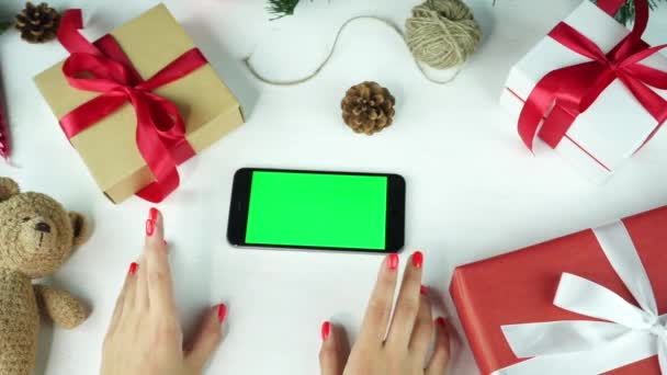 Dřevěné pozadí. Pohled shora. Černý smartphone se zelenou obrazovkou ležící na stole s vánočními sváteční výzdobou. — Stock video