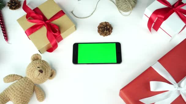 Sfondo in legno. Vista dall'alto. Smartphone nero con schermo verde sdraiato sul tavolo con decorazione natalizia . — Video Stock