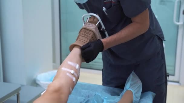 Chirurgien met en compression bas sur la jambe du patient après l'opération de la sclérothérapie. Concept de chirurgie vasculaire