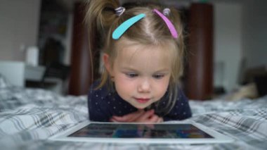 Halı döşemesinde dijital tablet teknolojisi kullanan meraklı anaokulu öğrencisi kız. Evde internette sörf yapan küçük bir çocuk. Çocuklar teknoloji bağımlılığı kavramı.