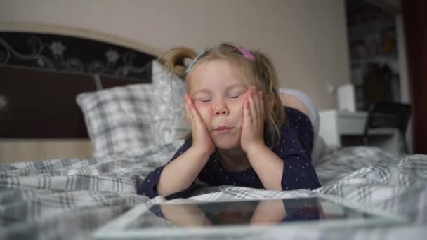 Nieuwsgierig schattig kleuter meisje met behulp van digitale tablet technologie apparaat liggen op tapijt vloer alleen. Klein kind te houden pad computer surfen internet spel thuis. Kinderen tech verslaving concept. — Stockvideo