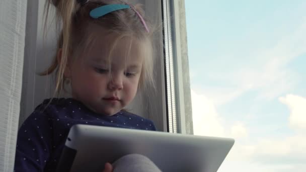 Curiosa niña linda preescolar utilizando tableta digital dispositivo de tecnología que se encuentra en el suelo de la alfombra solo. Pequeño niño mantenga la computadora de la almohadilla de navegación juego de Internet en casa. Concepto de adicción tecnológica infantil . — Vídeos de Stock