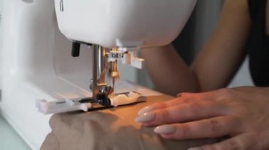 Kız dikiş makinesiyle bej kumaş dikti
