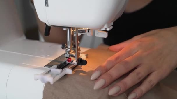 Девушка шьет бежевую ткань с помощью швейной машинки — стоковое видео