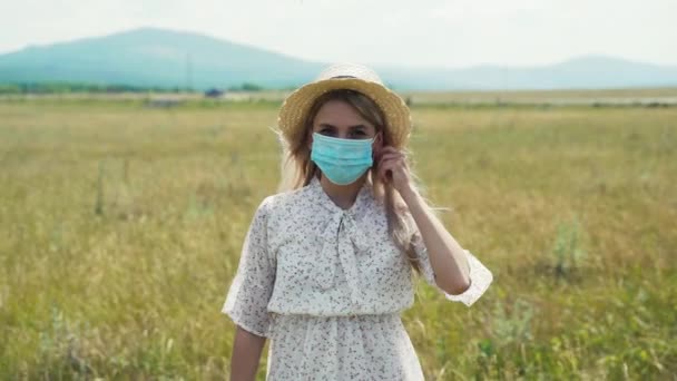 Vacker ung flicka i vit klänning och hatt med glad ansikte tar bort den skyddande masken. — Stockvideo
