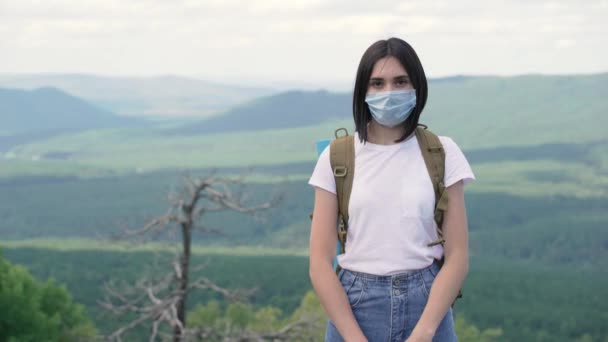 Retrato de chica seria en máscara protectora de pie en la cima de una montaña. — Vídeos de Stock