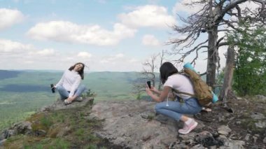Bir arkadaş için dağın tepesinde poz veren güzel bir kız..
