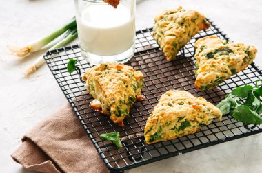 Bir tel raf üzerinde beyaz mozarella ve yeşil bitkilerle lezzetli çörekler. Beyaz taş zemin.