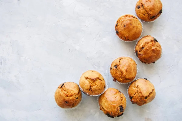 Muffins with chocolate chips and orange zest on a white stone background. Top view.