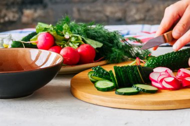 Sağlıklı salata yapımında taze sebze üzerinden. Kadının kesim salatalık bir ahşap tahta üzerinde eller. Adım adım kavramı pişirme.