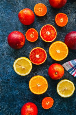 Taze olgunlaşmış Narenciye meyve karışımı. Kan portakal, mandalina, limon mavi taş zemin üzerine buz küpleri ile. Üstten görünüm.