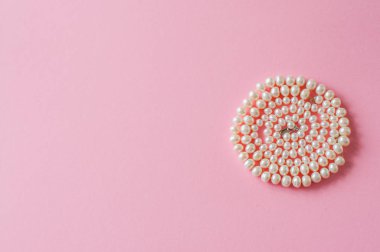 Düğün ya da moda kavramı. İnci kolye pembe bir arka plan üzerinde. Tonda.