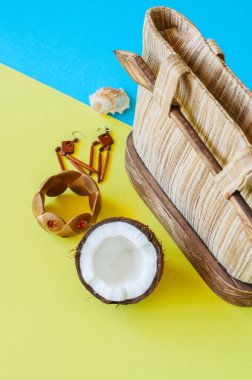Yaz tatili, Eko ve rahat tarzı kavramı. Moda rattan çanta, ahşap bileklik ve küpe Hindistan cevizi çift tonlu arka plan üzerinde. Üstten görünüm.