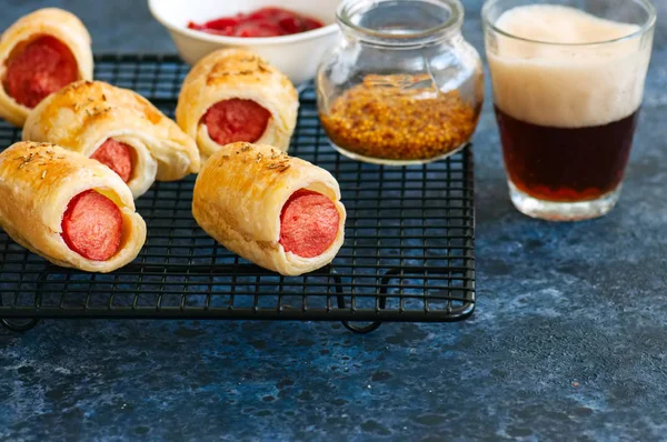 Bir planket domuzlar. Puf böreği sosis ile bir tel raf üzerinde rulo. Bira veya Fast food snack kavramı.