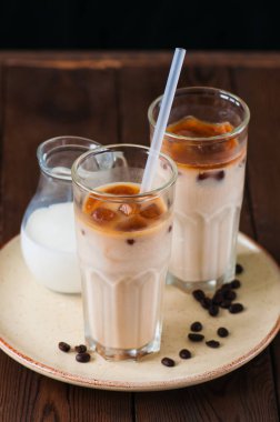 Uzun bir bardak buzlu kahve ahşap arka plan üzerinde bir tabakta servis.