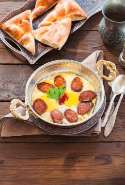 Türk kahvaltı - sosis (sucuk) ve baharat ahşap arka plan üzerinde bir tavada kızarmış yumurta.