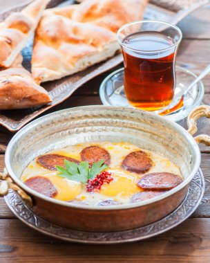 Türk kahvaltı - kızarmış yumurta ile bir tavada, bardak çay bir ahşap zemin üzerine baharat ve sosis (sucuk).