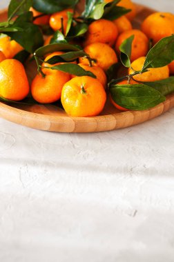 Mandalina beyaz taş zemin üzerine ahşap bir tabak içinde grubudur. Tonda.