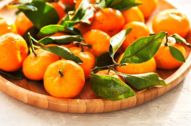 Mandalina beyaz taş zemin üzerine ahşap bir tabak içinde grubudur. Tonda.