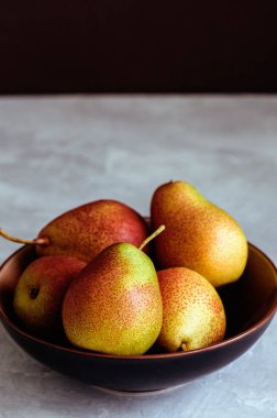 Beyaz taş zemin üzerine bir tabak içinde olgun armut grubudur. Yakın çekim. Kopya alanı.
