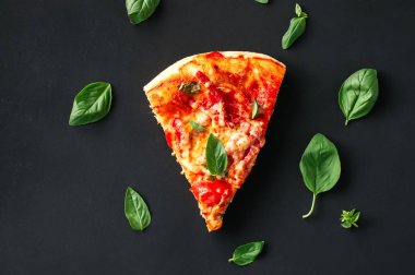 Bir parça pizza Fesleğenli siyah bir arka plan üzerine bırakır. Üstten görünüm, düz yatıyordu.