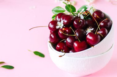 Pembe bir arka plan üzerinde beyaz bir kase taze Olgun Kiraz. Yakın çekim.