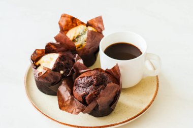 Muffins üç tür ve coffy bir plaka üzerinde bir fincan. Beyaz arka plan. Tonda.